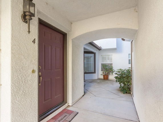 Entrance view of a house with an arched corridor and a brown door.
