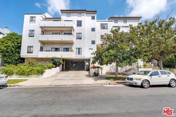 Front view of a multi-story apartment building with a gated entrance.