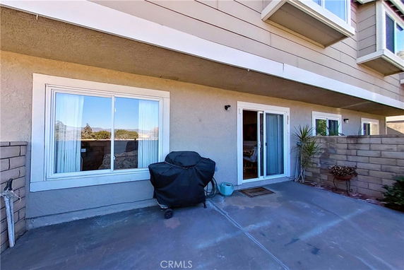 Back view of a house with large windows and sliding door leading to a patio.