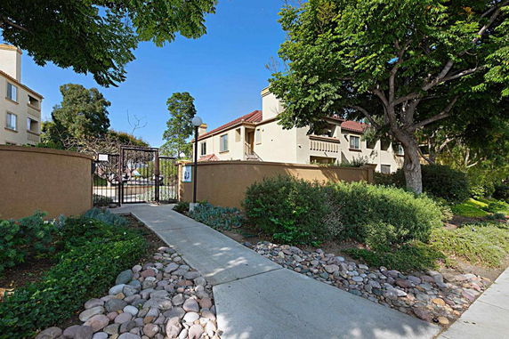 Front view of a house with a gated entrance and surrounding greenery.