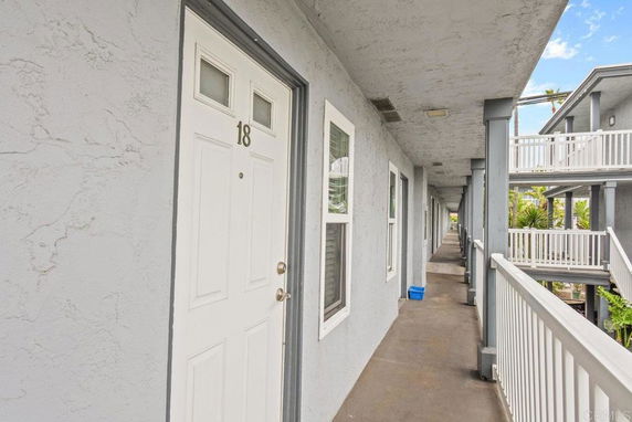 View of an apartment building hallway with doors and windows along the corridor.