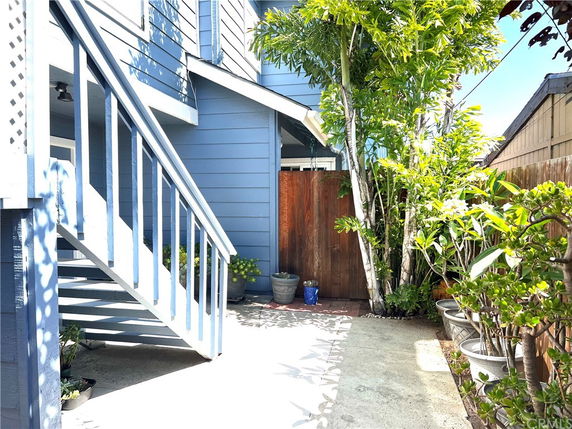 Front view of a two-story house with stairs and plants in the foreground.