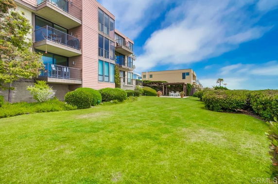 View of modern multi-story building with balconies and a landscaped lawn area.