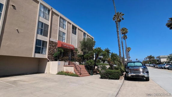 Front view of a multi-story building with large windows and an entrance canopy labeled Cape May Towers.
