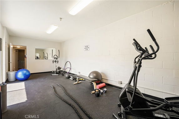 Room equipped with gym equipment including an elliptical, stability ball, and exercise mats.