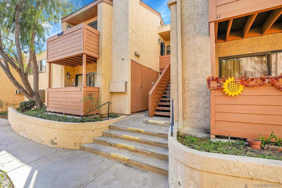 Front view of a multi-story apartment building with balconies and stairs.