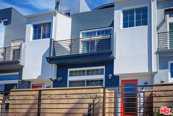 Front view of a modern multi-story townhouse with balconies and red doors.