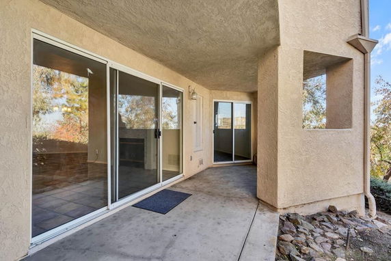 Exterior covered patio area of a house with sliding glass doors.