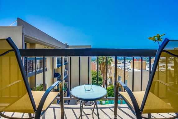 View of surrounding buildings from a balcony with chairs and table.