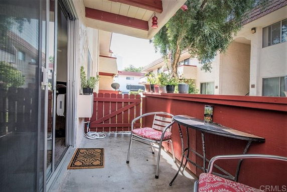 View from a small outdoor patio with chairs and a table overlooking neighboring buildings.