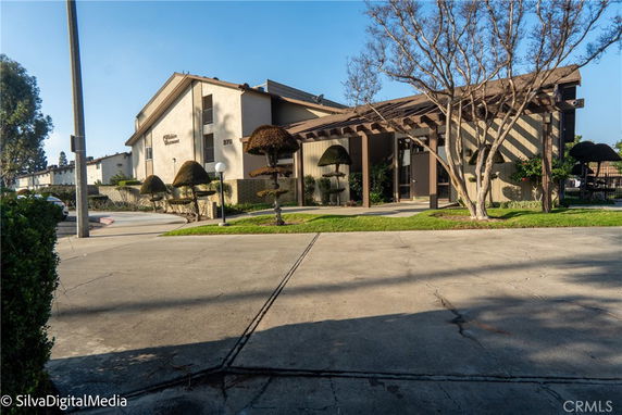 Front view of a building with a sloped roof and entrance covered by a pergola.