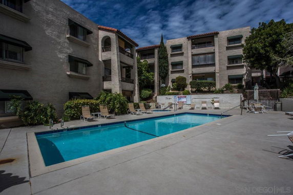 Outdoor area with a swimming pool surrounded by multi-story buildings.