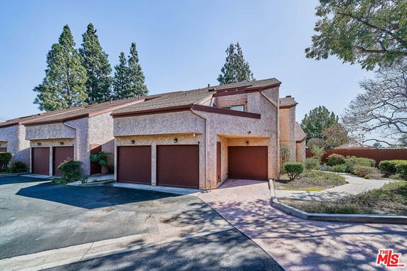 Front view of a townhouse with a single garage and sloped roof.
