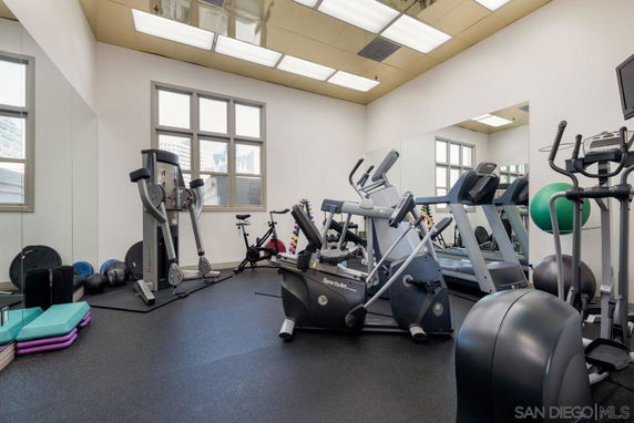 Indoor gym with exercise equipment and mirrors on the wall.
