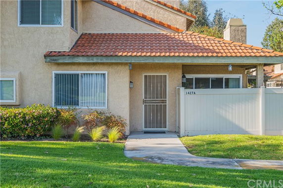 Front view of a house with a tiled roof and a fenced entryway.