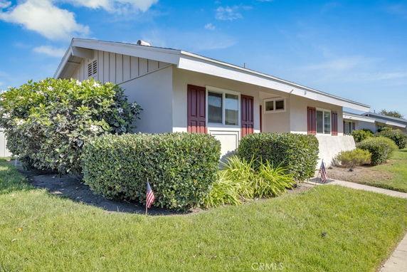 Front view of a single-story house with white exterior and red shutters.