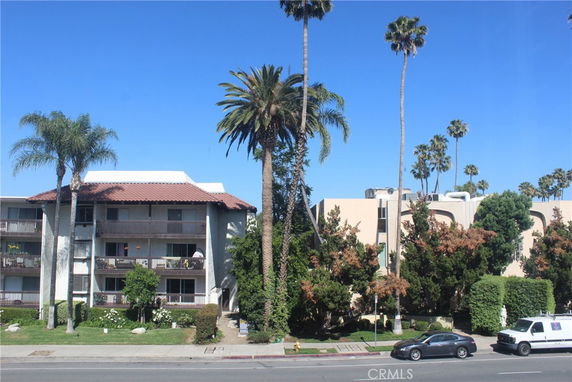 Front view of a multi-story residential building with balconies and a tiled roof.