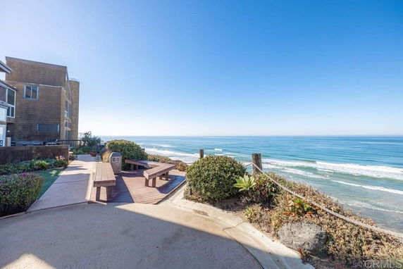 Panoramic ocean view from a building with outdoor seating area and landscaped surroundings.