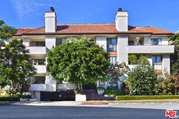 Front view of a multi-story residential building with a tiled roof and balconies.
