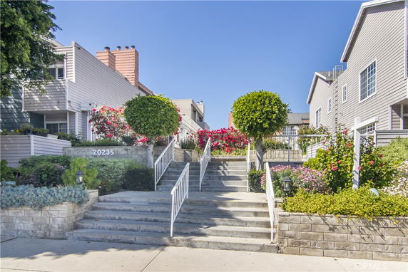 Front view of a two-story residential building with stairs and landscaped garden.