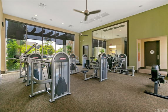 Indoor gym area with various exercise machines and large windows.