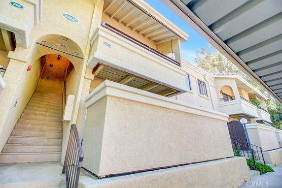 Front view of a multi-story residential building with balconies and an external staircase.