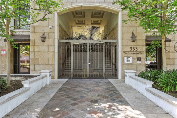 Front view of a building with a gated entrance and pathway leading up to it.