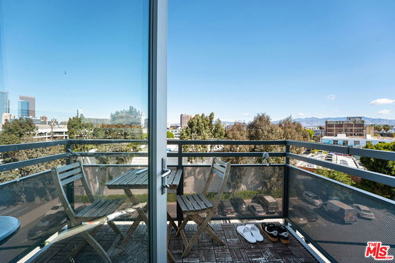 A balcony with a table and chairs overlooking a cityscape.