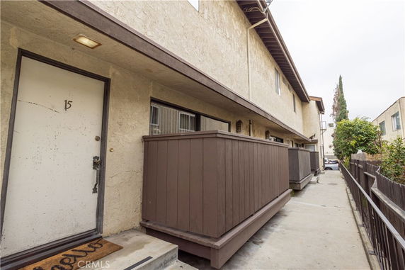 Front view of a two-story apartment building with balcony railings and an exterior corridor.