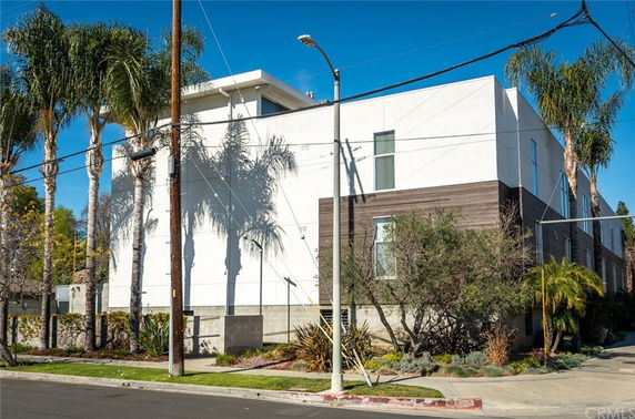 Front view of a modern multi-story building with a flat roof and large windows.