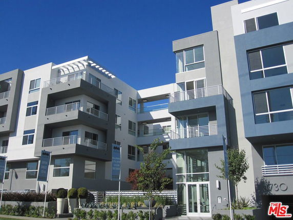 Front view of a modern multi-story apartment building with balconies and large windows.