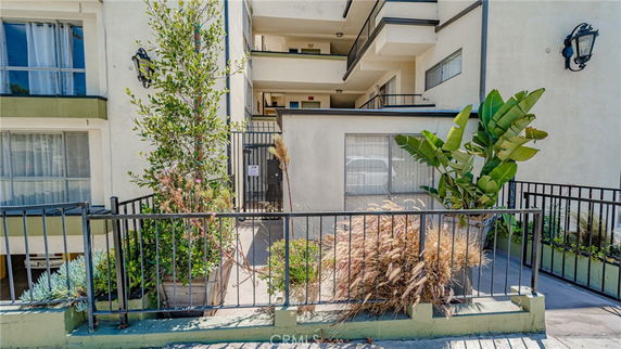 Front view of a multi-story building with balconies and potted plants.