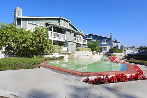 Front view of a multi-story house with balconies and a landscaped garden area.