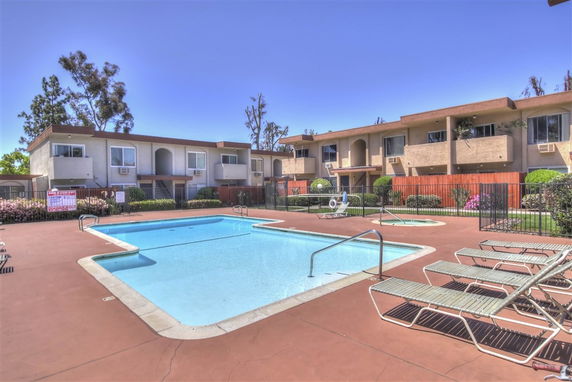 Outdoor view of a swimming pool area in front of a building with multiple units.