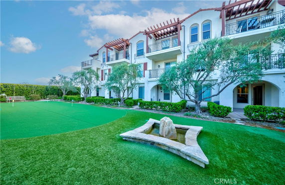 Front view of a multi-story residential building with balconies and landscaped garden.