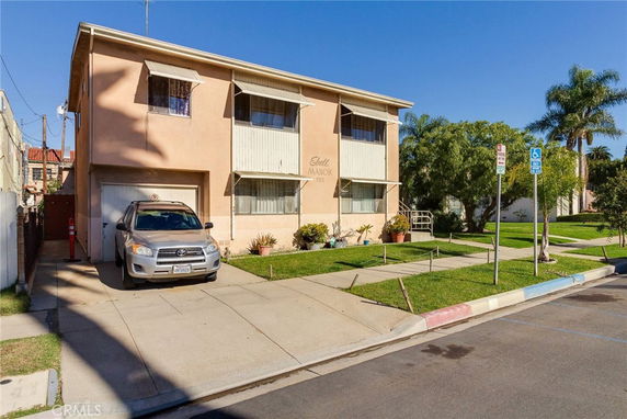 Front view of a two-story apartment building with a car parked in the driveway.
