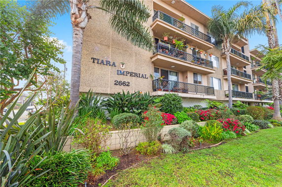 Front view of a multi-story apartment building with balconies and landscaping.