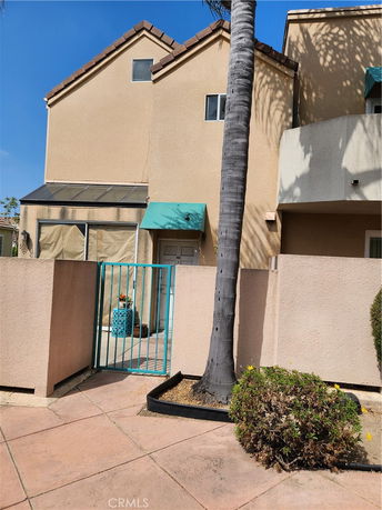 Front view of a multi-story house with a small gate and a teal awning.