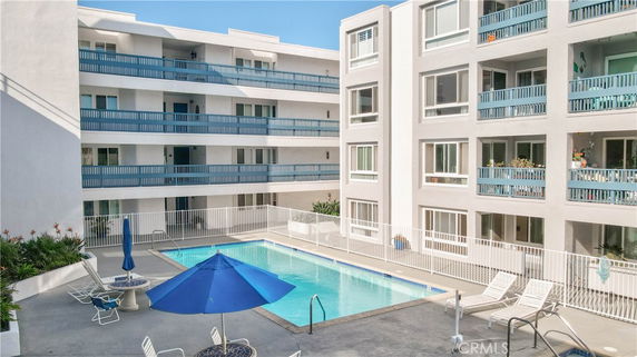 Outdoor swimming pool area surrounded by multi-story building with balconies.