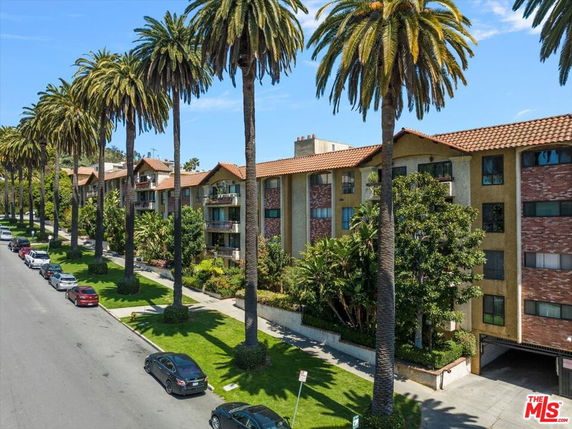 Front view of a multi-story apartment building with balconies and tiled roof.