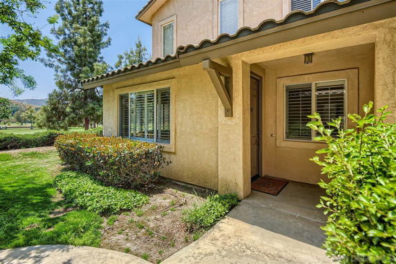 Front view of a two-story house with a tiled roof and shrubs.
