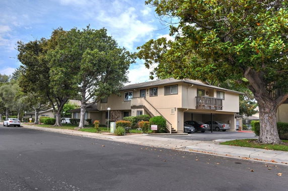 Front view of a two-story residential building with an external staircase and covered parking underneath.