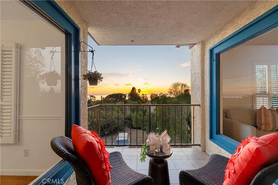 Balcony with two chairs overlooks a scenic sunset view.