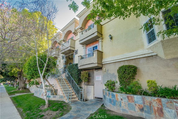 Front view of a multi-story residential building with a staircase leading to the entrance.