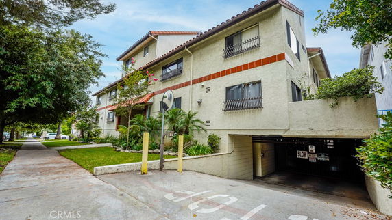 Front view of a multi-story residential building with a gated parking entrance.