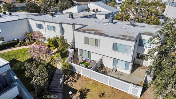 Aerial view of a residential building with a flat roof and fenced patio area.