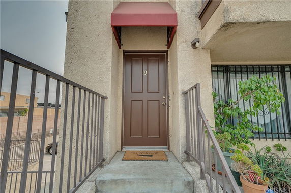 Front view of an apartment entrance with a brown door and small red awning.