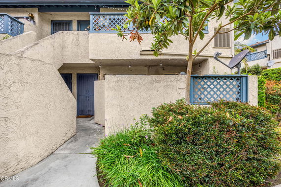 Front view of a multi-unit residential building with beige exterior and blue accents.