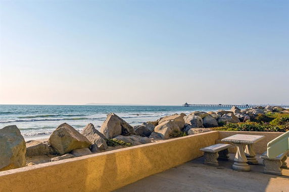 Panoramic view of the ocean from a stone patio with a table and benches.