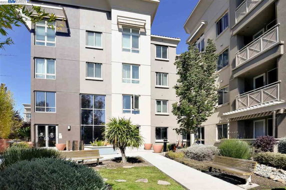Front view of a multi-story residential building with balconies and large windows.